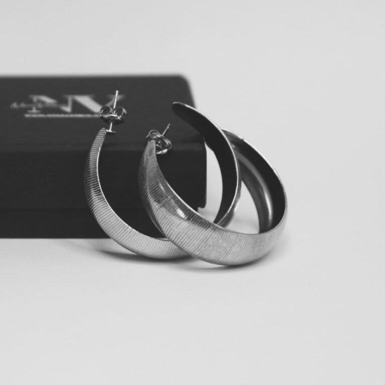 עגילי חישוק לינה כסף מונחים ליד קופסת תכשיטים שחורה