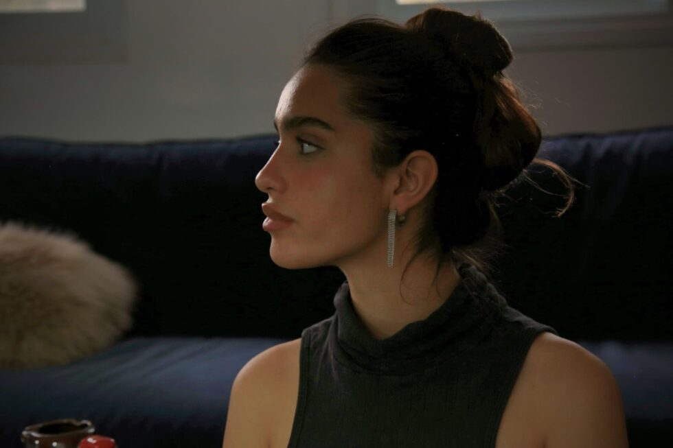 דוגמנית יושבת על ספה כהה עונדת עגילי לורן כסף