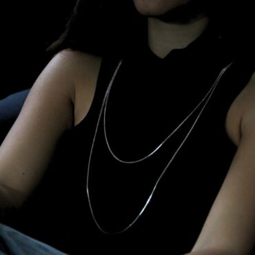 שרשרת כסופה ארוכה, על גבי חולצה שחורה של אישה, כשהיא עונדת אותה בתצוגה כפולה